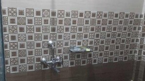 Een badkamer met een douche, een blauwe emmer en een klein plankje met een beker.