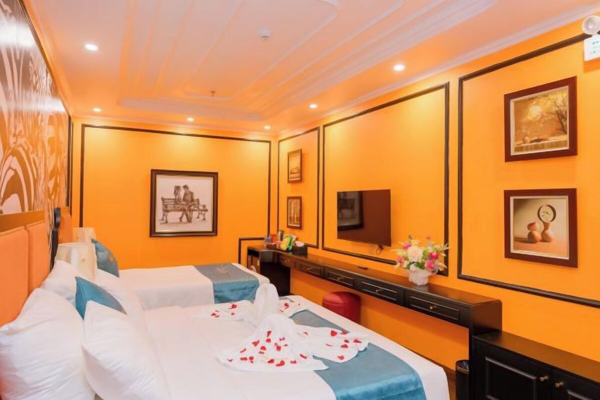 A hotel room with two beds, a large mirror, and framed artwork on the walls.