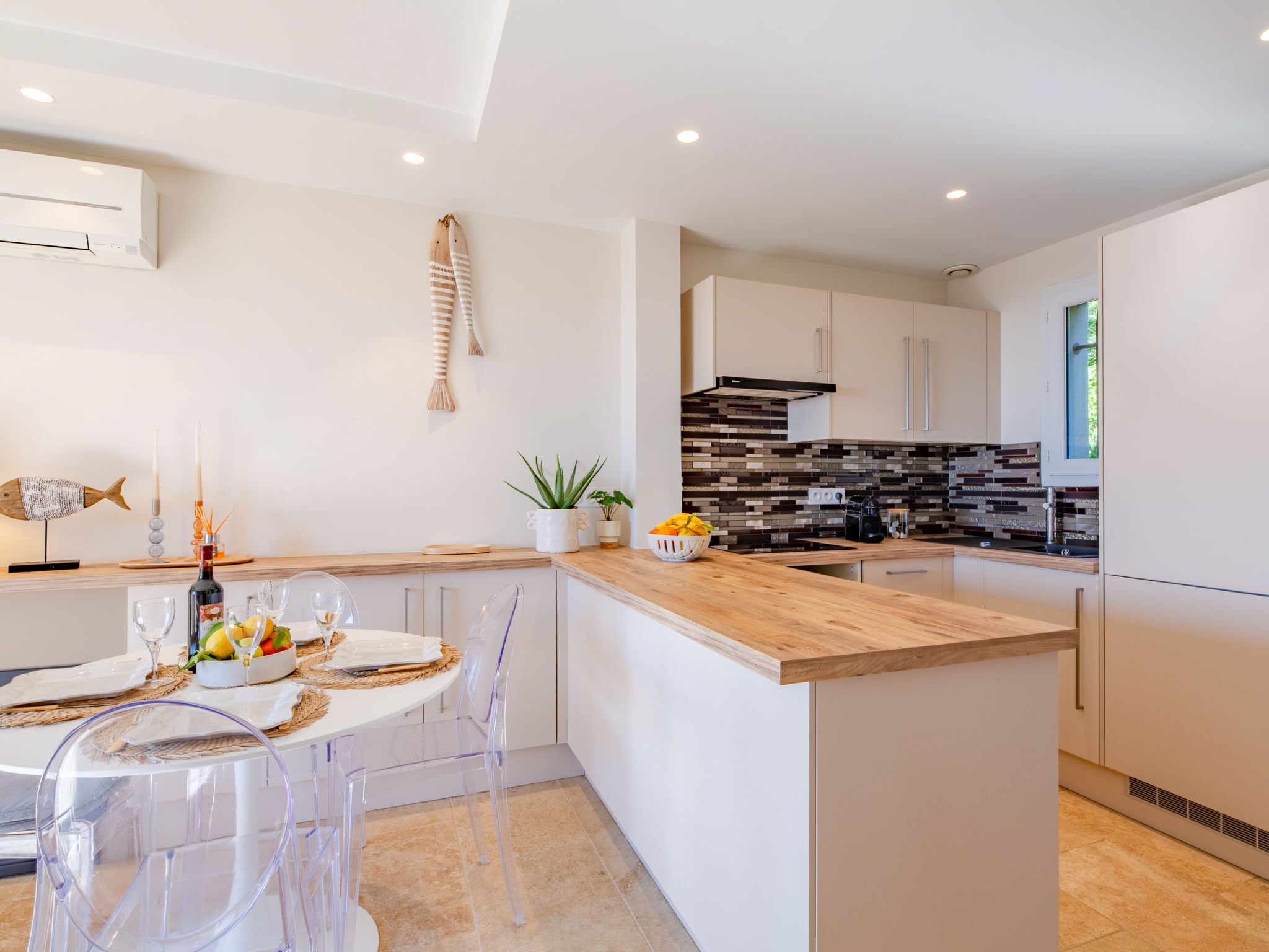 A modern kitchen with a wooden island, white cabinetry, and a black and white backsplash.