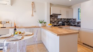 A modern kitchen with a wooden island, white cabinetry, and a black and white backsplash. - Le Bougainvillier by Interhome (Sainte Maxime)