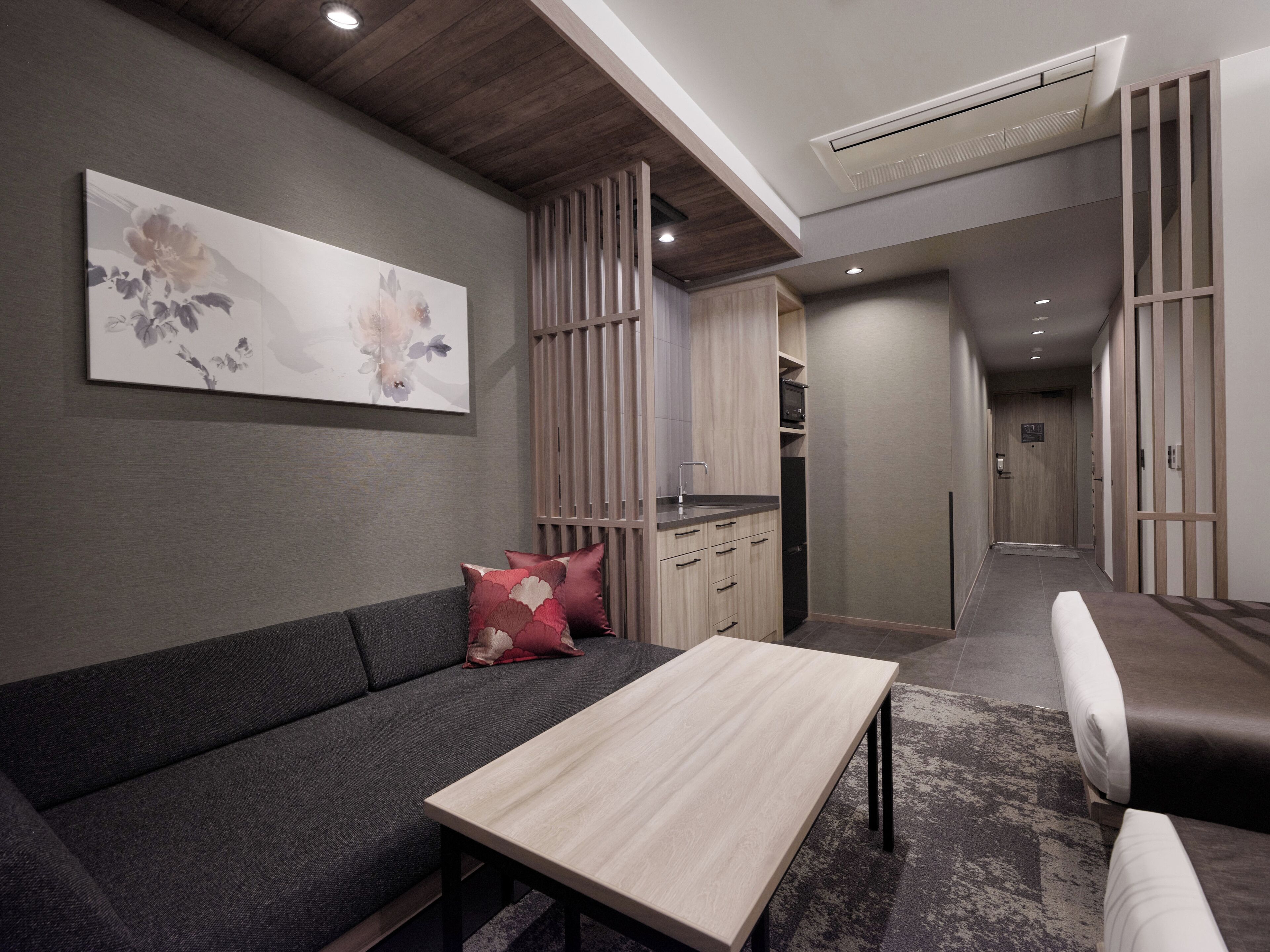 A modern living room with a sofa, a coffee table, and a kitchen area in the background.