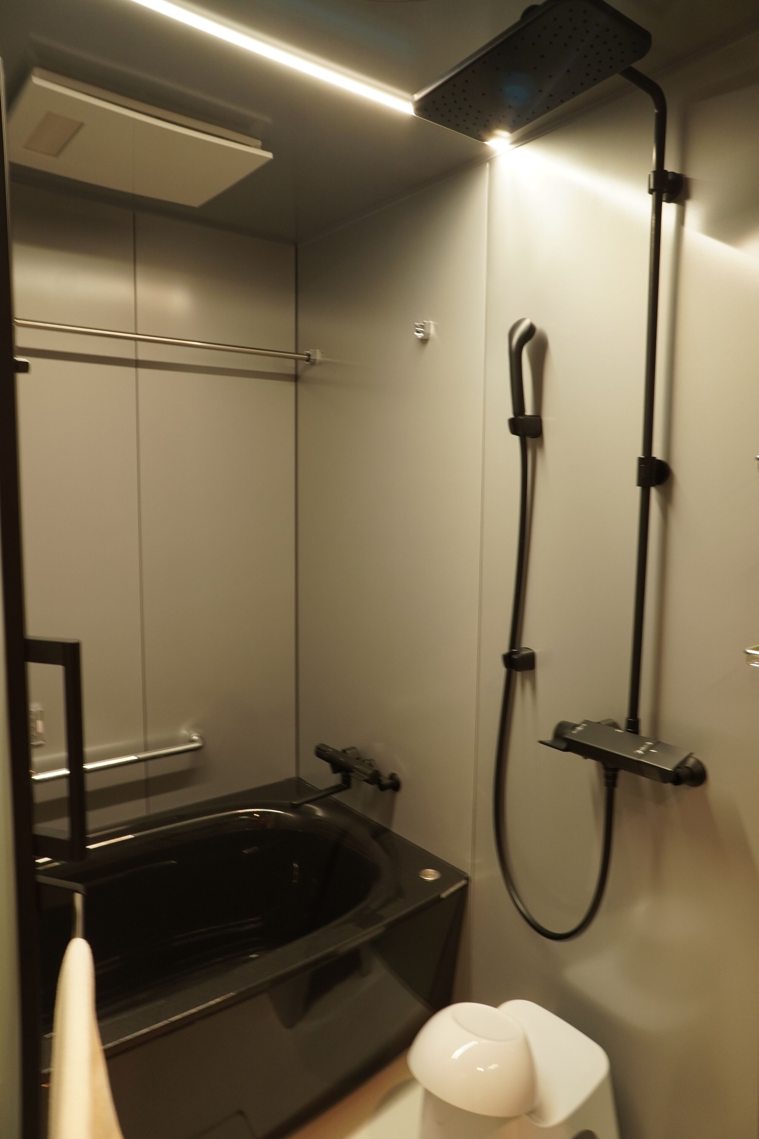 Un baño moderno con una bañera negra, un cabezal de ducha y un inodoro.
