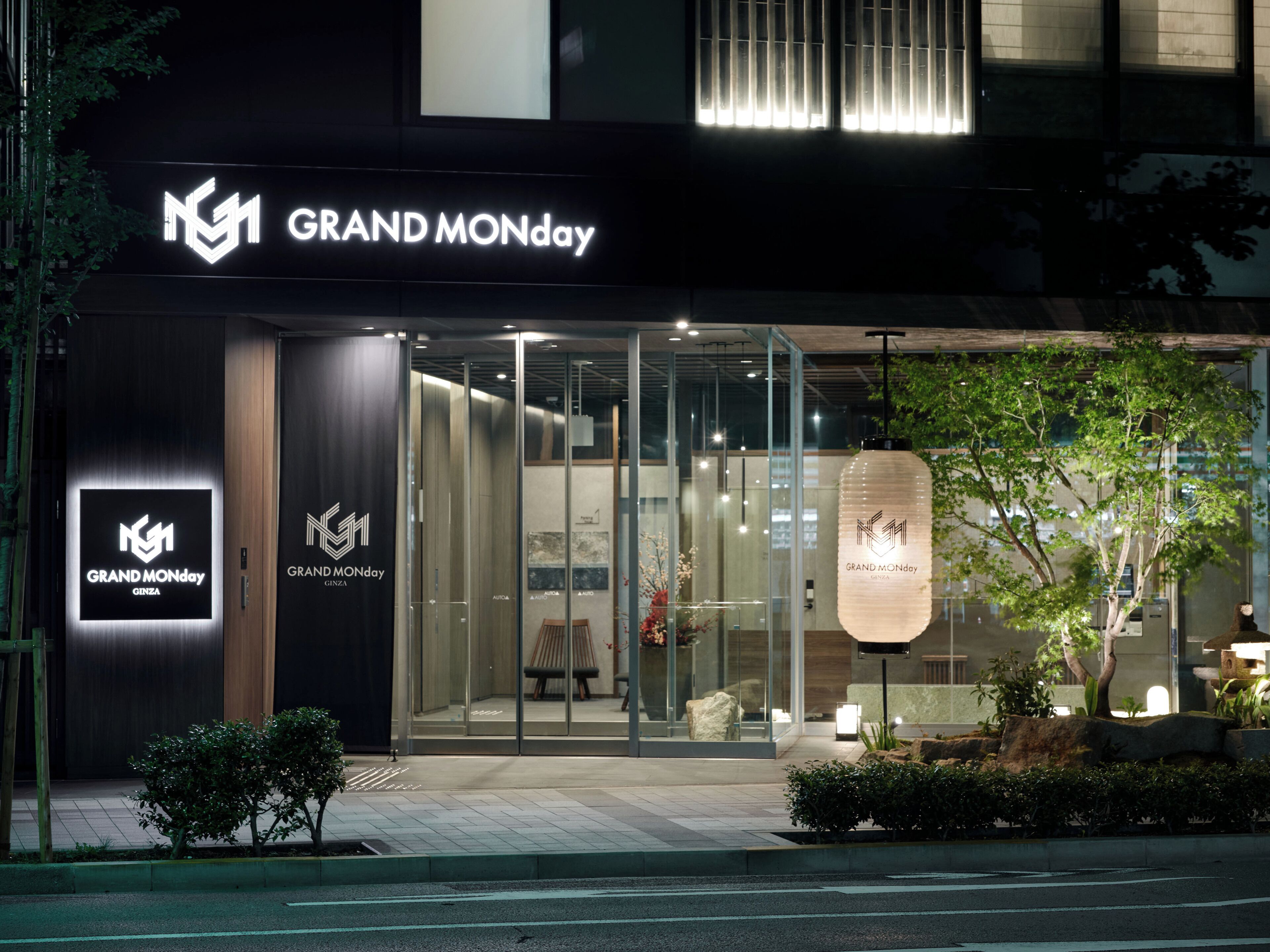 The exterior of a GRAND MONDAY Ginza store with glass doors, a modern facade, and a well-lit entrance.