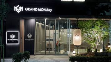 The exterior of a GRAND MONDAY Ginza store with glass doors, a modern facade, and a well-lit entrance.