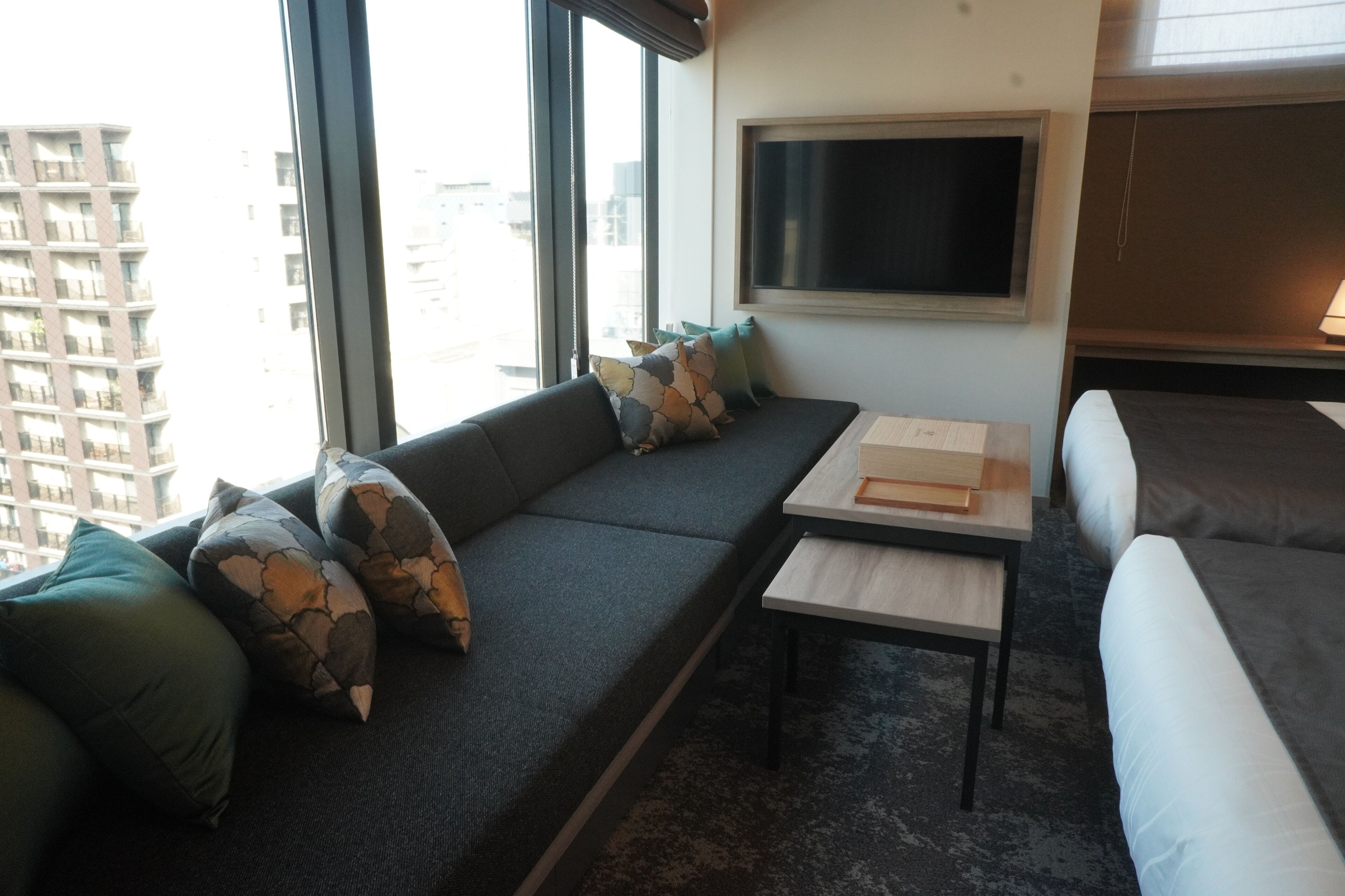 En moderne stue med en sofa, et lille bord og et fjernsyn ophængt på væggen.