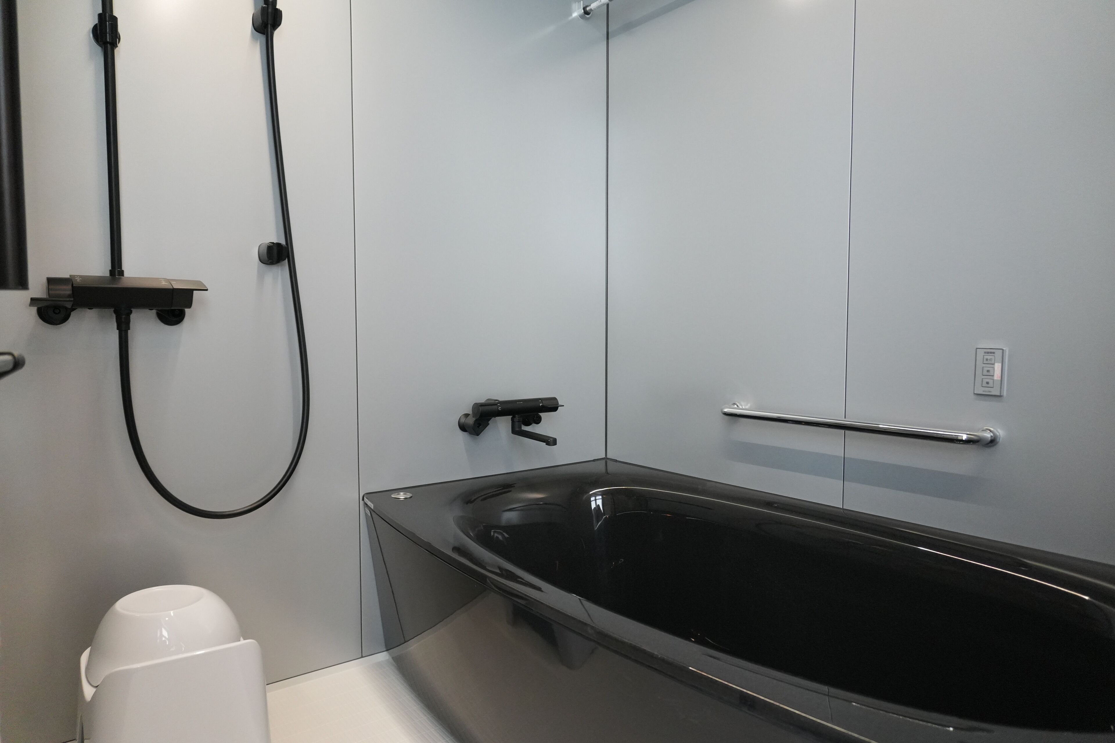 A modern bathroom with a black bathtub, a white toilet, and a shower area.