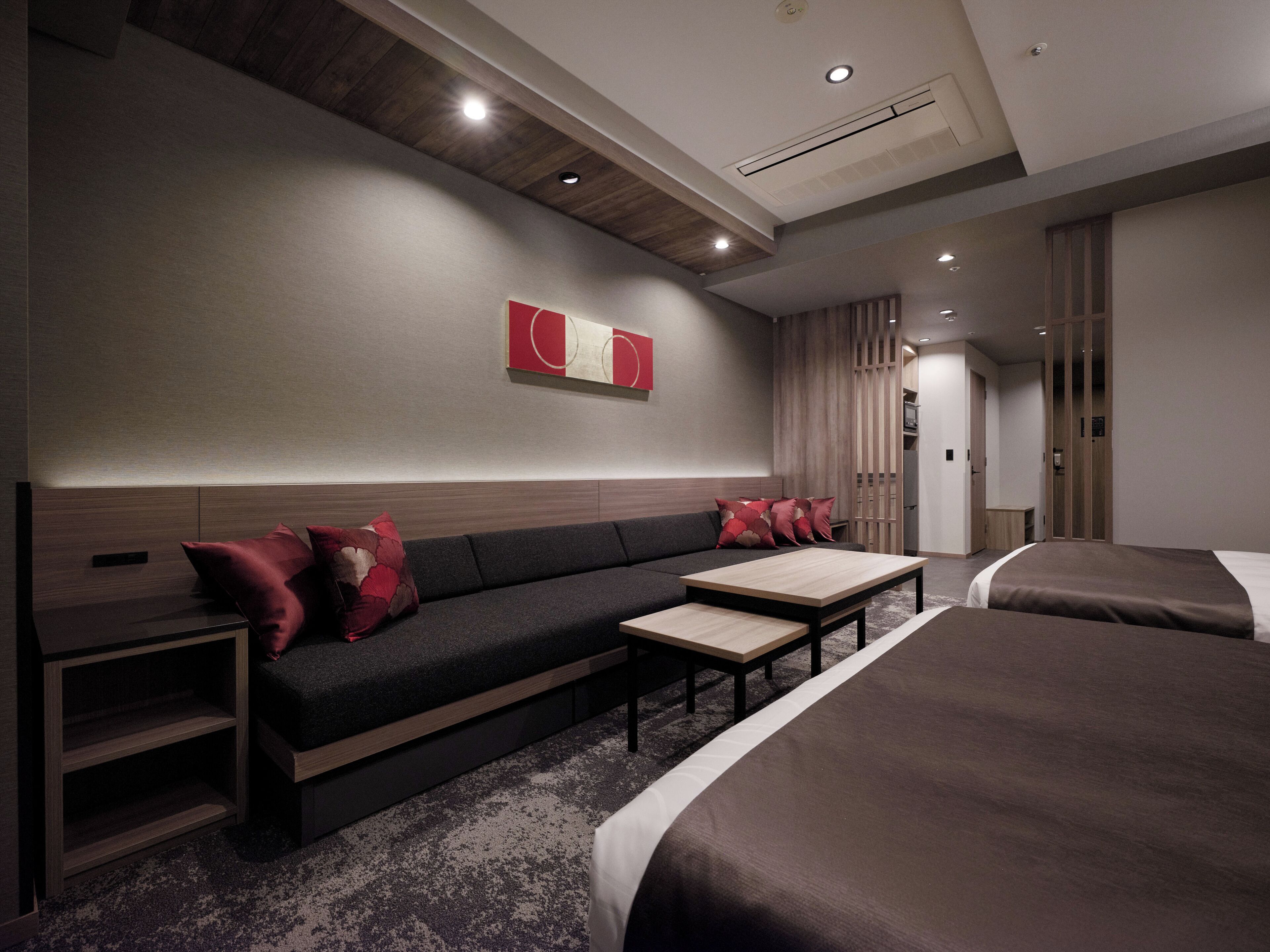 Une chambre d’hôtel moderne équipée d’un canapé, de deux lits, d’une petite table et d’un meuble.