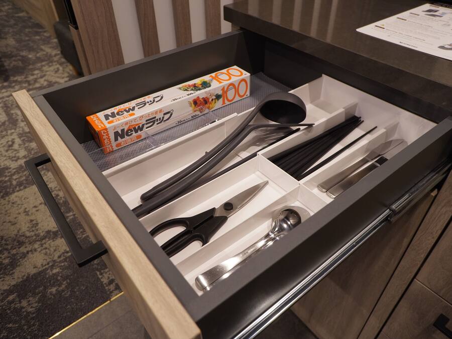 Un tiroir contenant des ustensiles de cuisine rangés avec soin, notamment des ciseaux, une cuillère et une spatule.