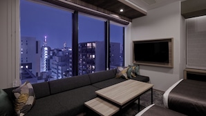 A modern living room with a large window, a sofa, a coffee table, and a flat-screen TV. - GRAND MONday GINZA (Tokyo)