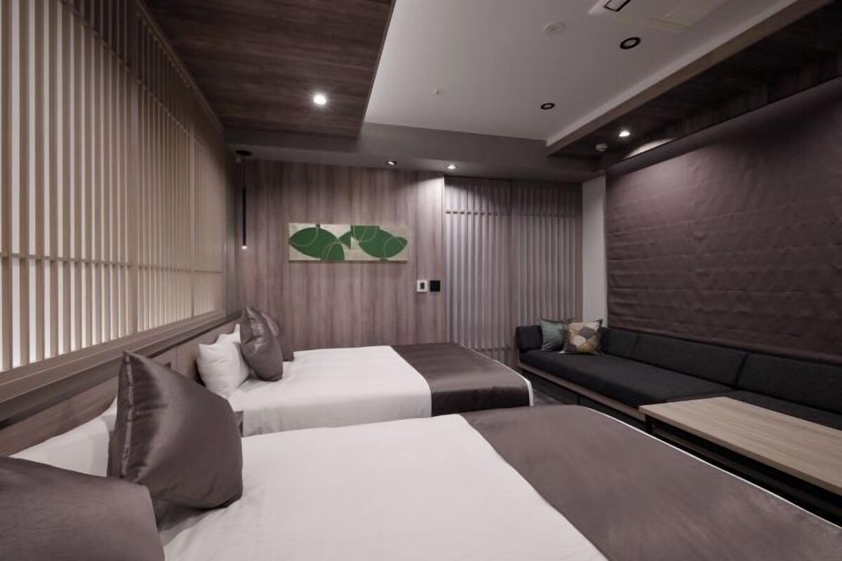 Une chambre d’hôtel moderne avec deux lits, un canapé et un plafond en bois.