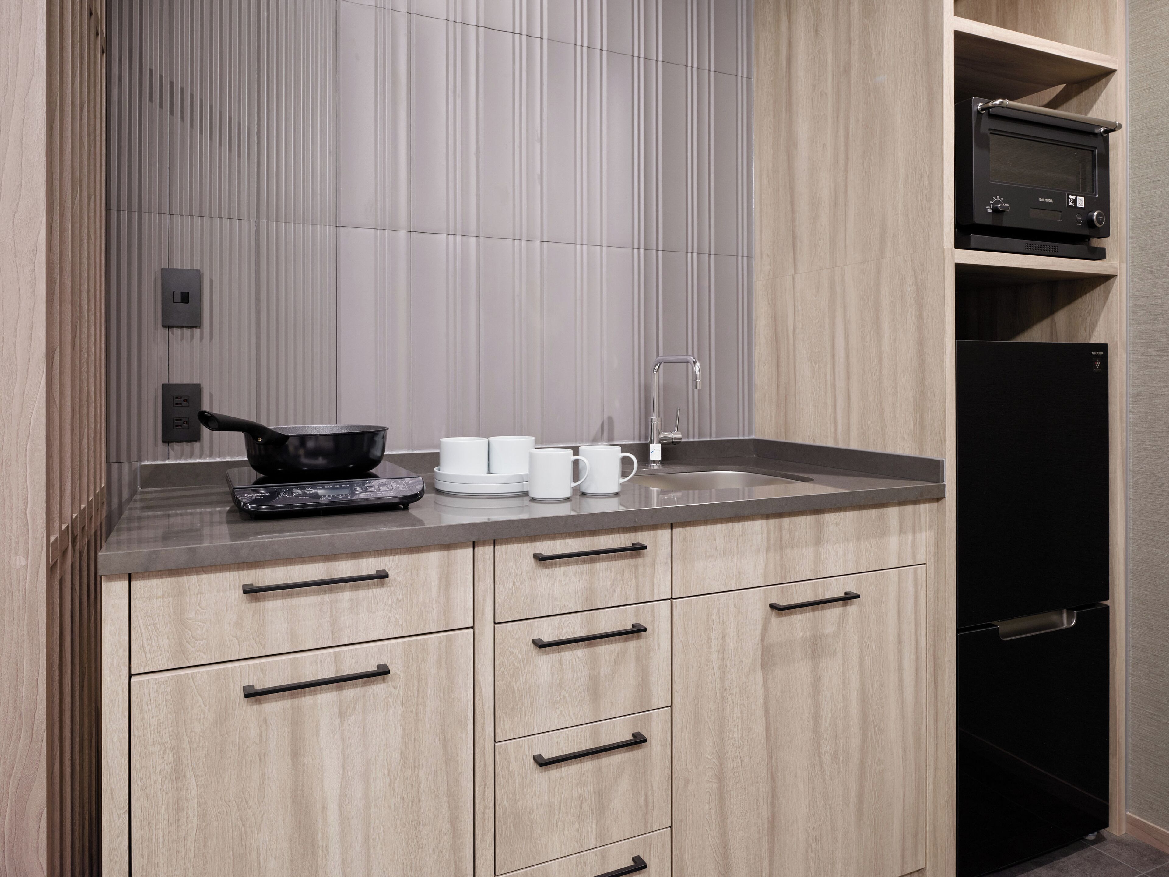 A modern kitchen with a built-in oven, a sink, and a black refrigerator.