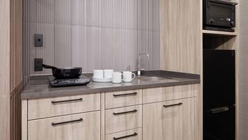 A modern kitchen with a built-in oven, a sink, and a black refrigerator.