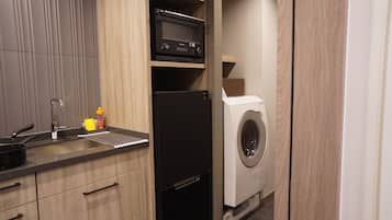 A compact kitchen with a sink, stove, microwave, and a washing machine.