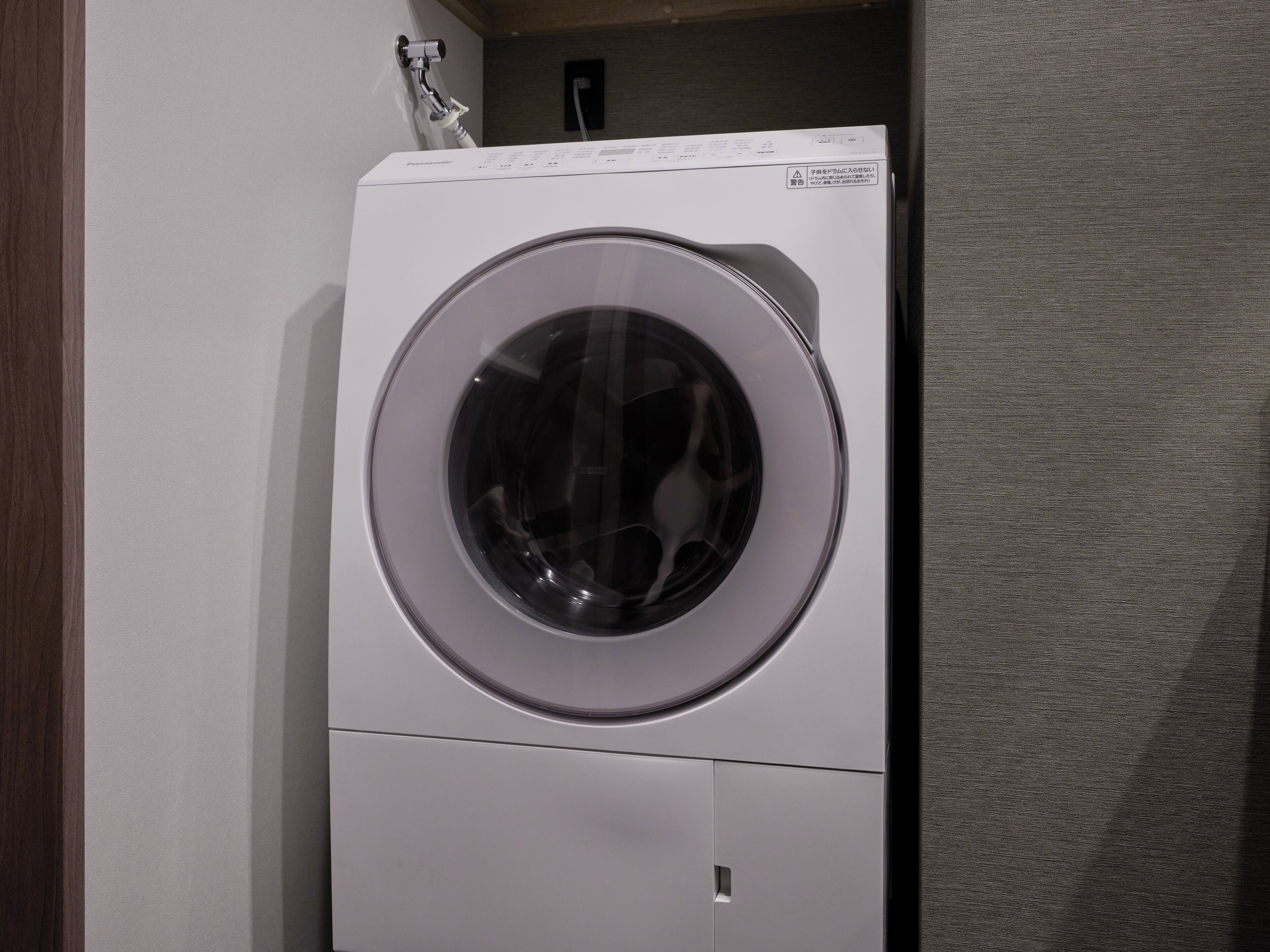 A front-loading washing machine in a laundry room.