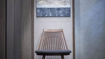 Ein modernes Interieur mit einem Holzstuhl und einem strukturierten Kunstwerk an der Wand.
