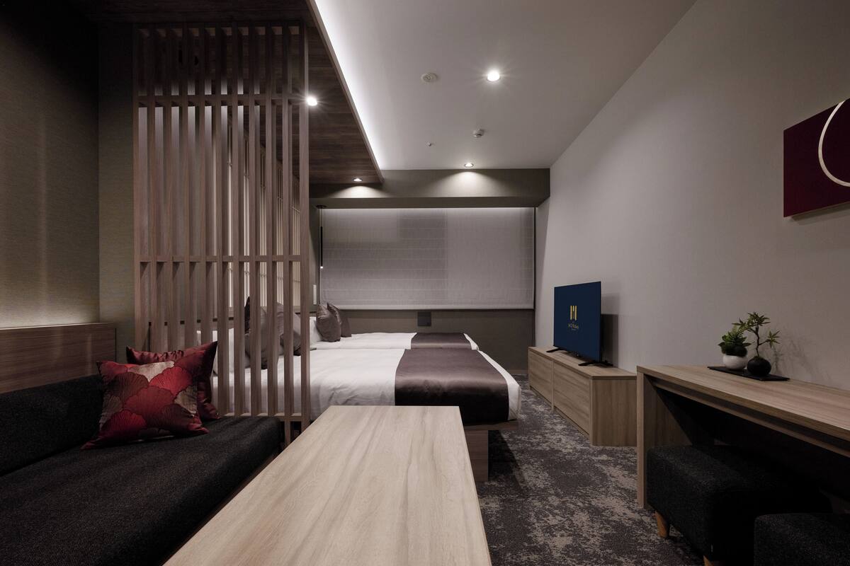 Una habitación de hotel moderna con cama, sofá, escritorio y televisión.