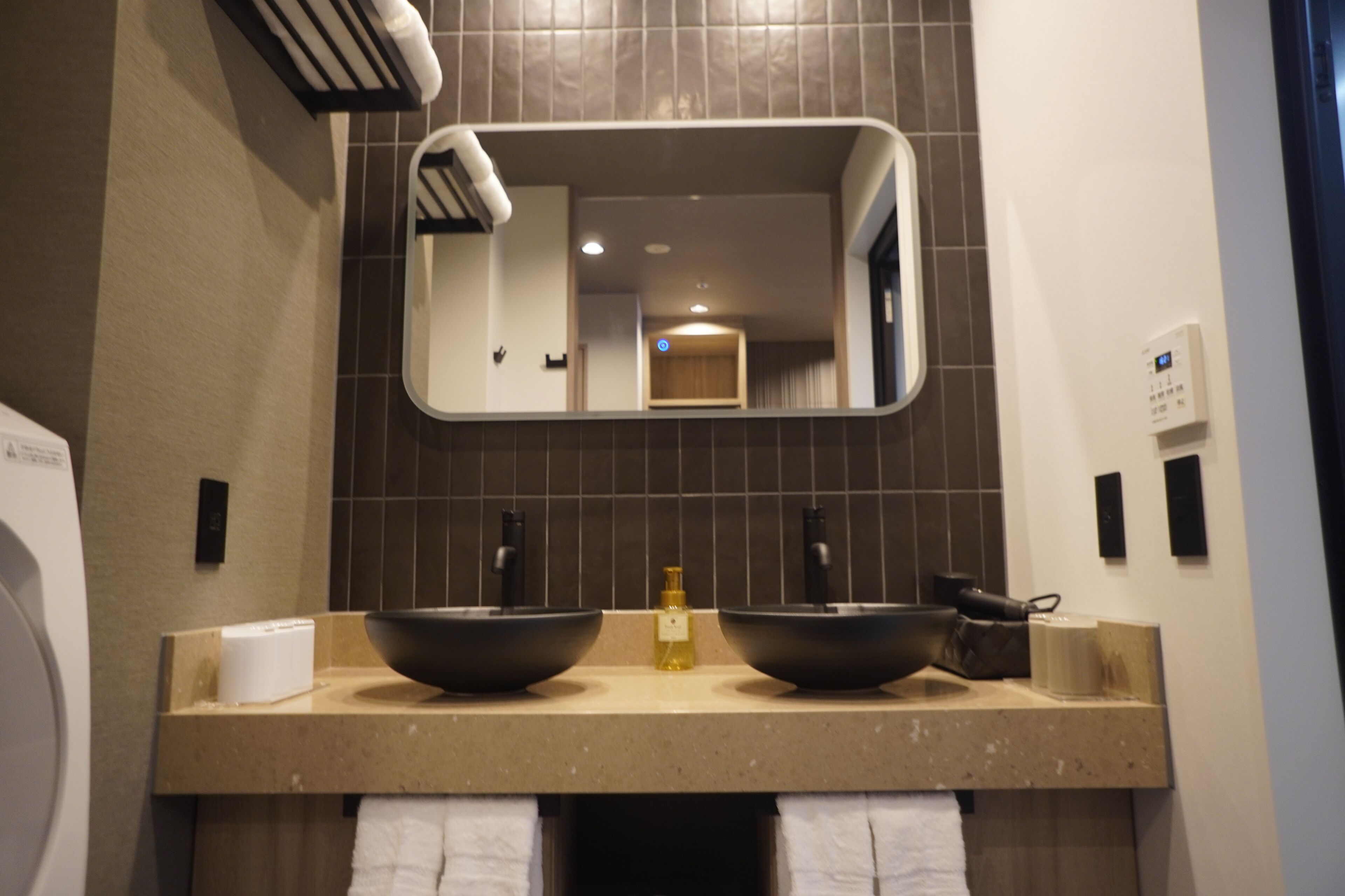 Un baño con dos lavamanos, un espejo y un perchero para toallas.