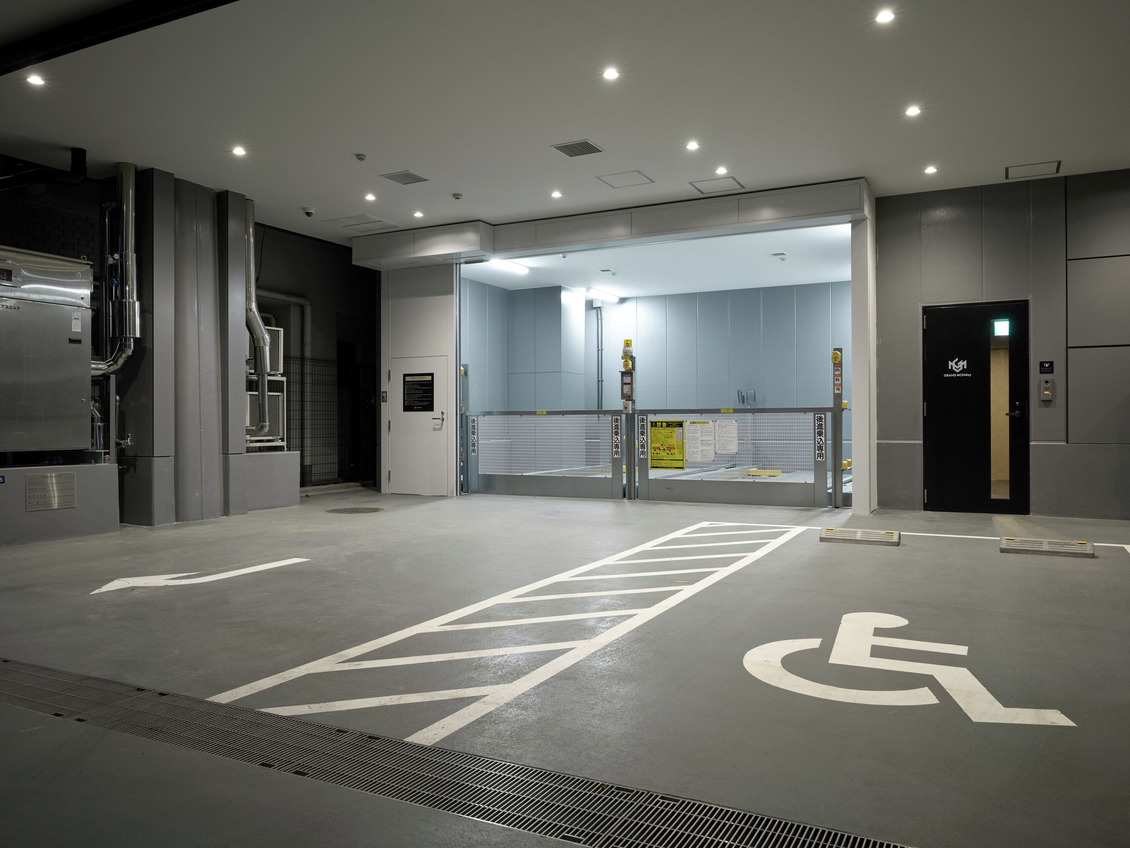 A modern, well-lit indoor space with a wheelchair-accessible area marked on the floor, a door labeled "Grand Hallway," and a visible ventilation system.