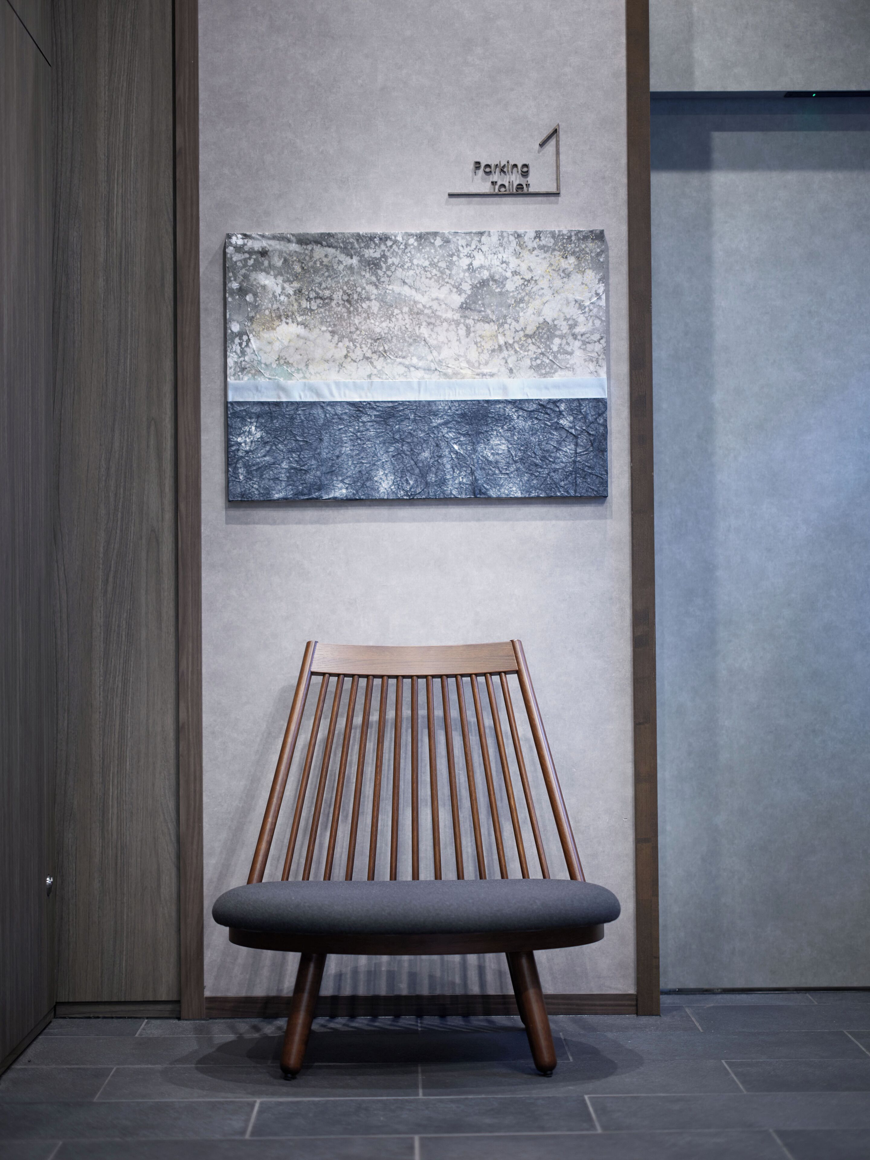 Eine Bank mit modernem Design, ein an der Wand befestigtes Schild für eine Parktoilette und ein reliefartiges Wandkunstwerk.