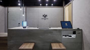 A reception desk with a logo, a laptop, a phone, and a printer.