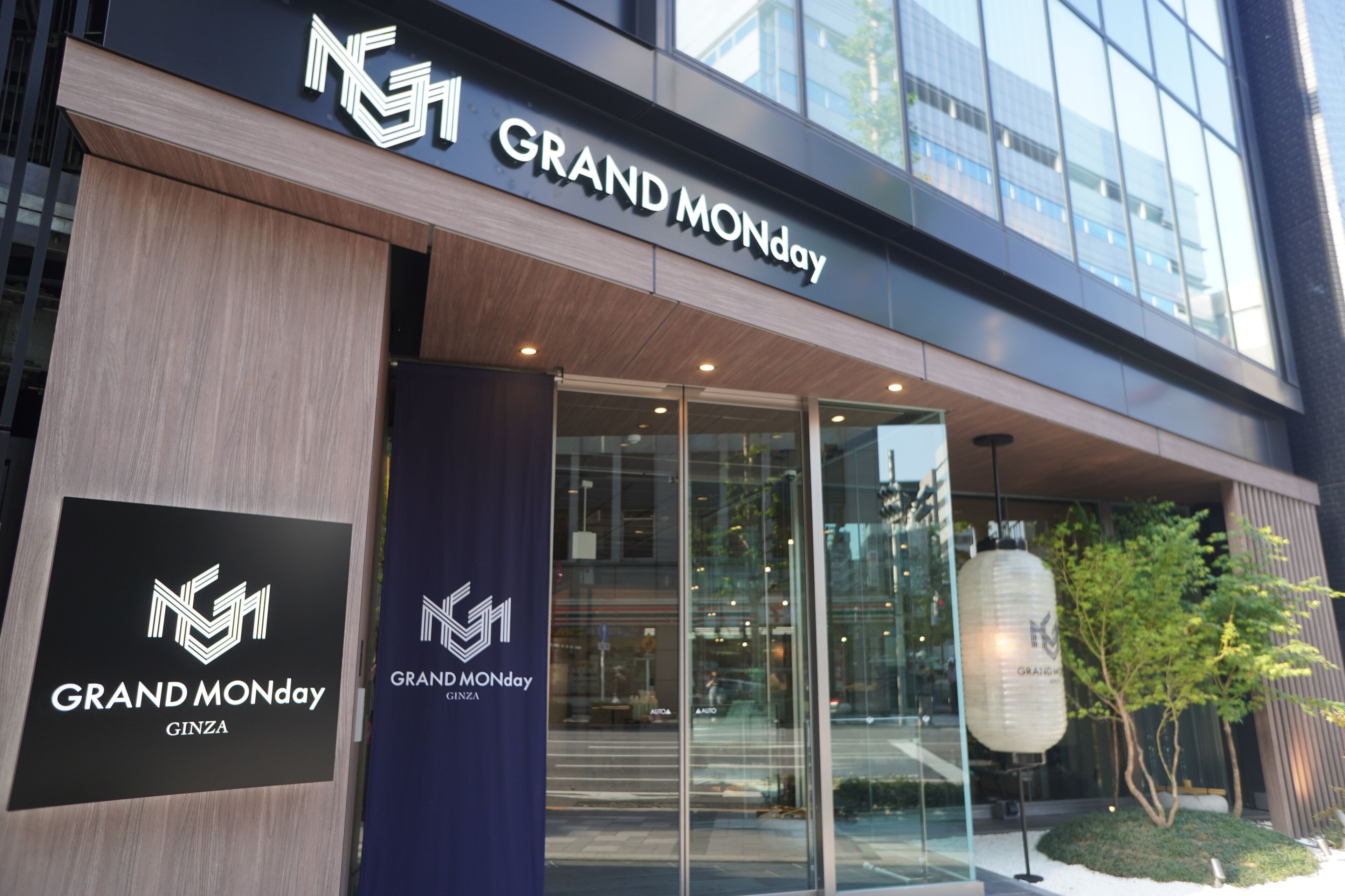 The exterior of a Grand Monday Ginza building with a modern design, featuring large glass windows and a prominent entrance.