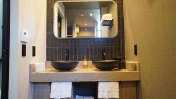 Un baño con dos lavamanos grandes, un espejo encima y toallas colgadas debajo.