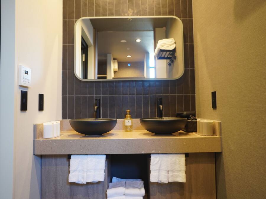 Un baño con dos lavamanos grandes, un espejo encima y toallas colgadas debajo.