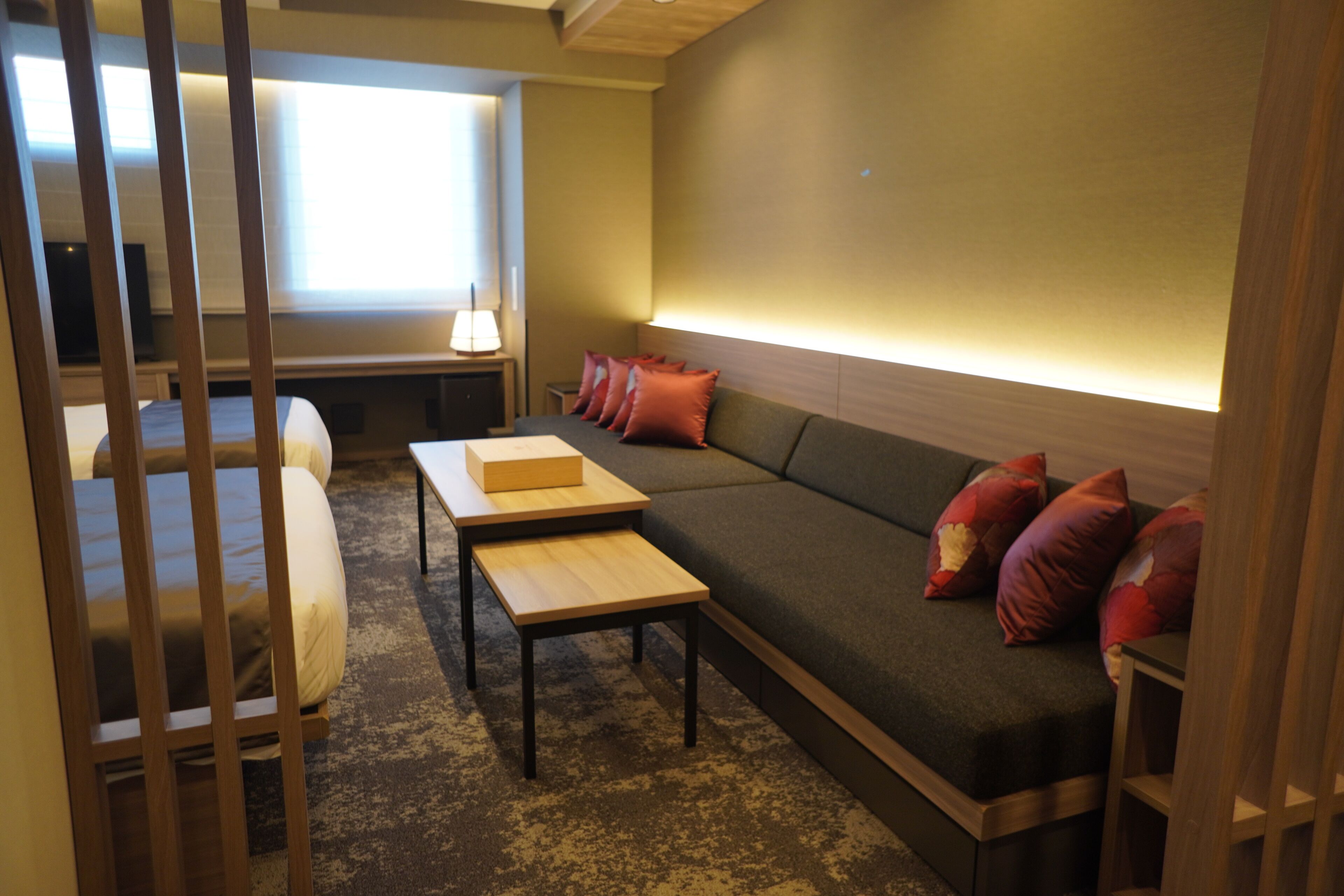 Een moderne hotelkamer met een bank, een houten tafel en een televisie.