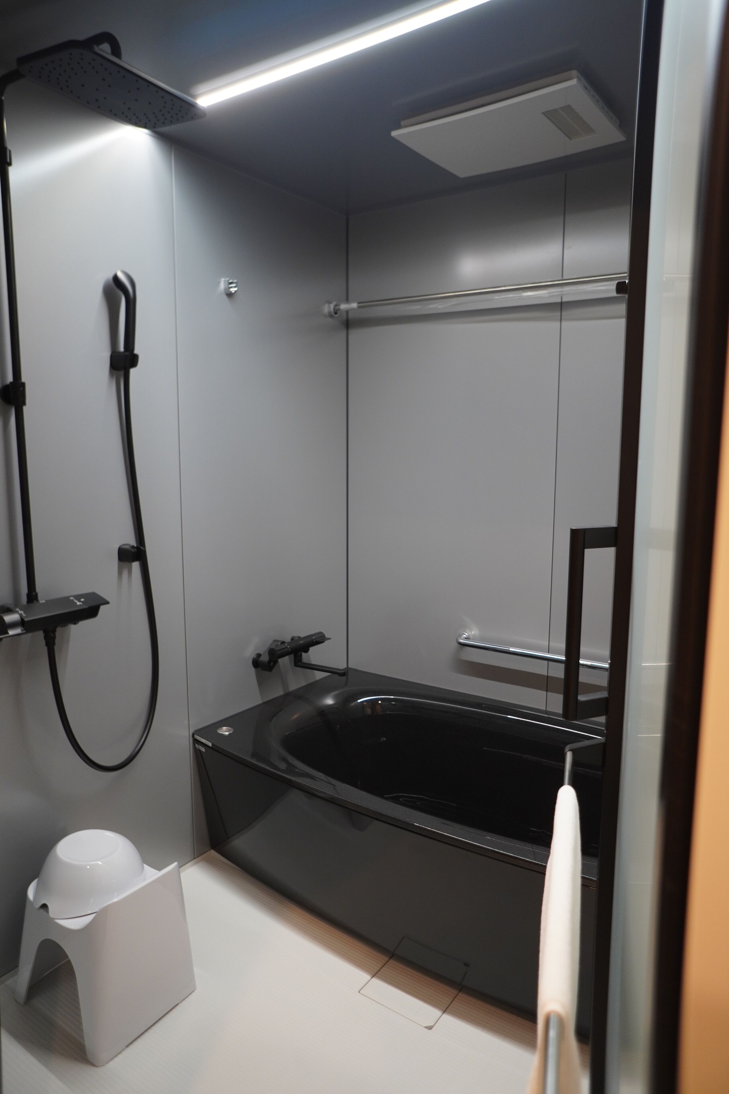 A modern bathroom with a black bathtub, a showerhead, and a towel rack.