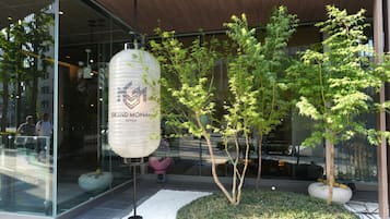 A modern building with glass windows, a hanging lantern, and a small tree in the foreground.