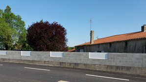 A road with a concrete barrier and a building with a red-tiled roof. - Furnished studio (Montaigu-Vendée)