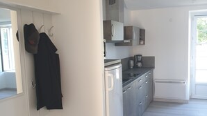 A modern kitchen with white cabinets, a built-in oven, and a coffee machine. - Furnished studio (Montaigu-Vendée)