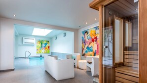 A modern interior with a pool area, white furniture, and abstract art. - Villa Euphrosina (Ostend)