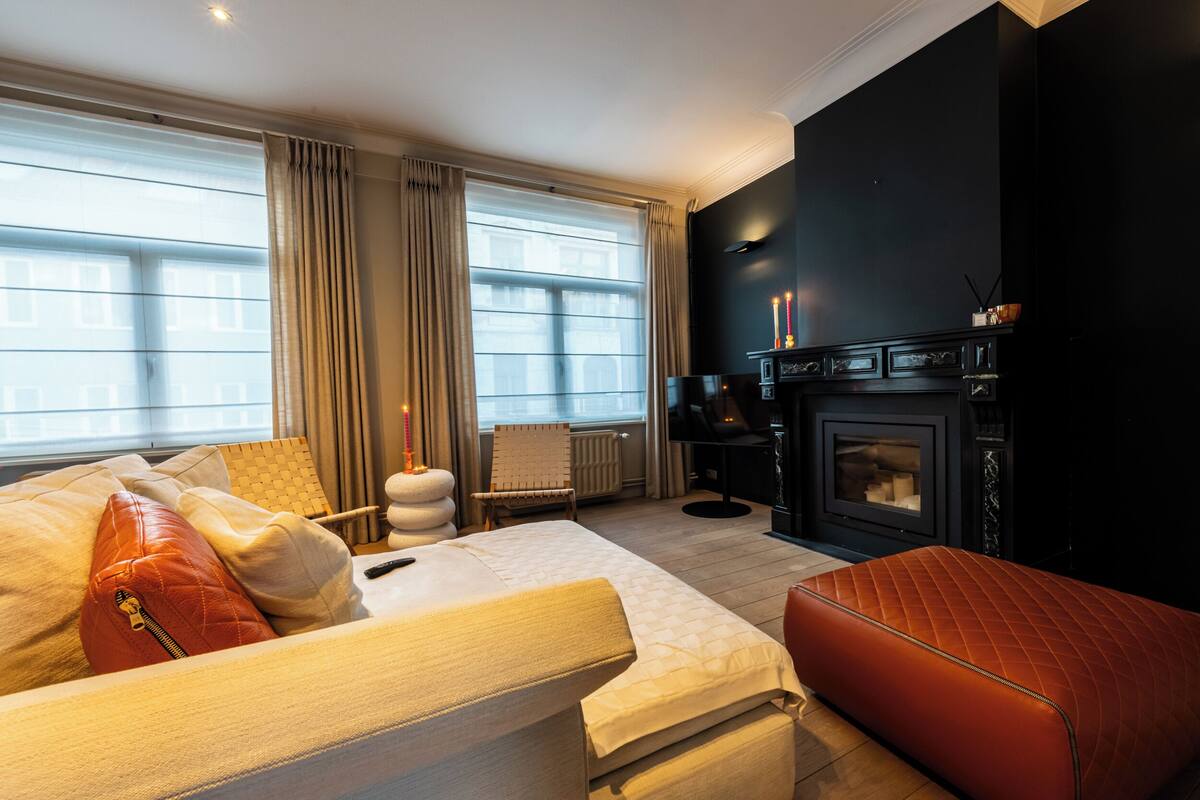 Une chambre d’hôtel moderne dotée d’un grand lit, d’un coin salon et d’une cheminée.