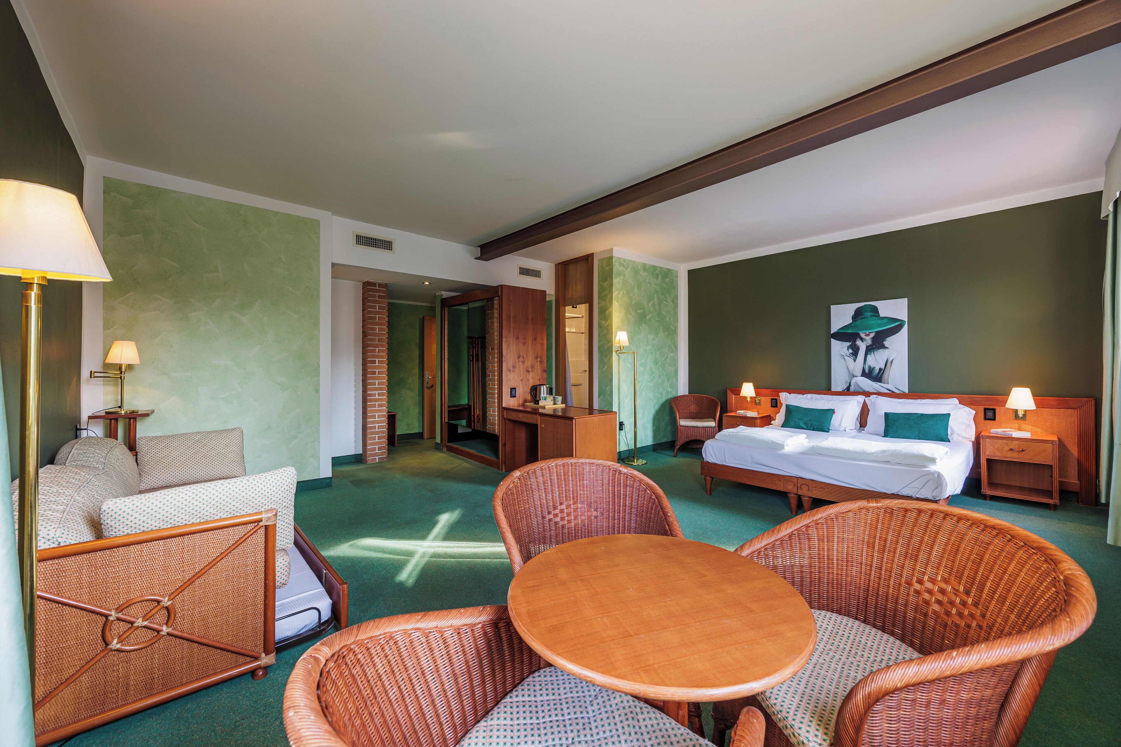 Una habitación de hotel con una cama, dos sillas, una mesa y un escritorio con una lámpara.