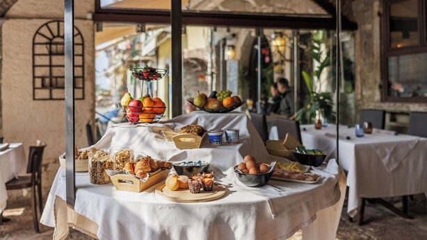Un bufé de desayuno con diferentes alimentos y un bol de frutas sobre una mesa en un restaurante con decoración rústica.