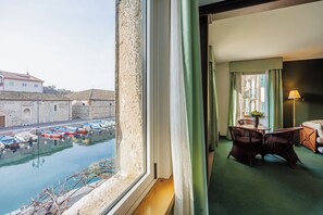A room with a view of a harbor, a dining area with wicker furniture, and a lamp. - Hotel Alla Grotta (Lazise)