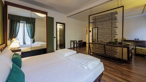 Una habitación de hotel con una cama grande, un espejo, un escritorio y una zona de estar.