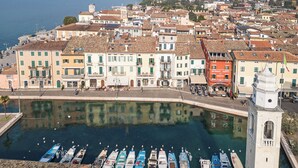 Un pueblo costero con un puerto deportivo, edificios históricos y una torre destacada.
