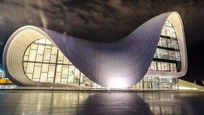 Een modern architectonisch gebouw met een golvend ontwerp, grote ramen en een spiegelende vloer.