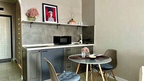 Une cuisine compacte équipée d’un four à micro-ondes, d’un évier et d’un petit coin repas avec deux chaises.
