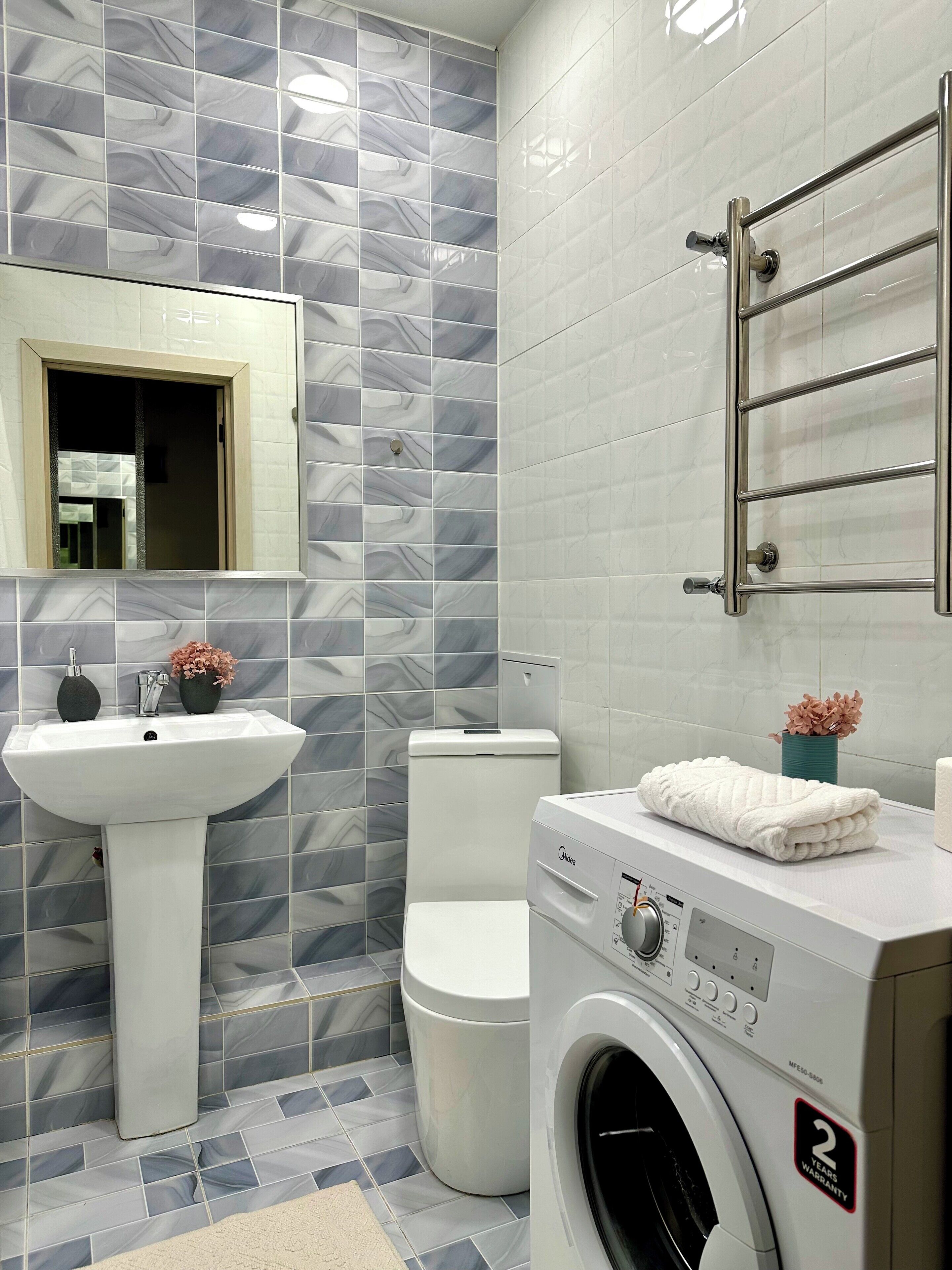 A bathroom with a sink, toilet, and washing machine.