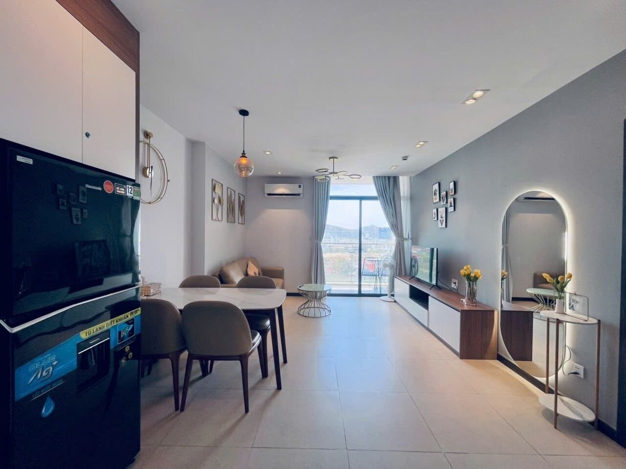 Un salon moderne avec un coin repas, un grand téléviseur et une vue sur la ville.