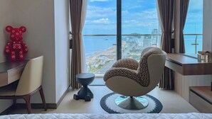 Een moderne woonkamer met uitzicht op zee, een rode beer-vormige decoratie en een unieke fauteuil.