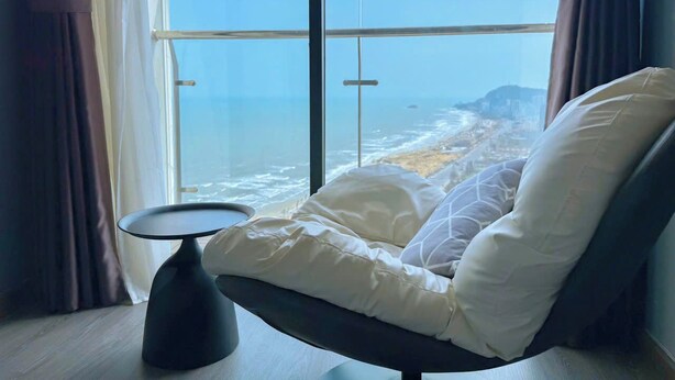 Een moderne kamer met een groot raam, met uitzicht op zee en een eiland in de verte.