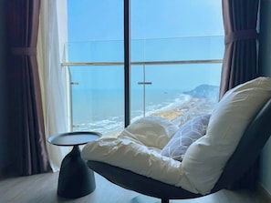 A modern room with a large window offering a view of the sea and a distant island.