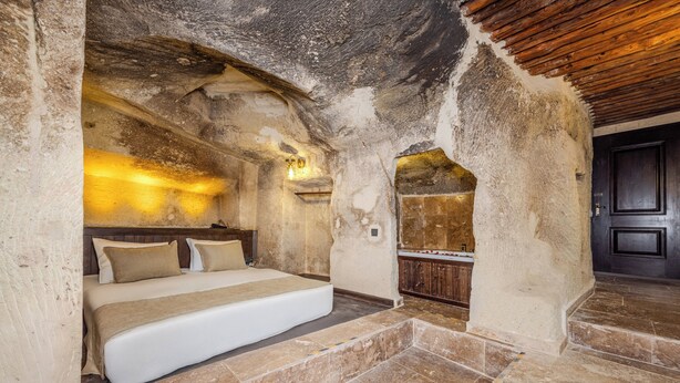 Ein Schlafzimmer mit einem Bett, Holzboden und einer Steinwand.