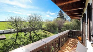 Un balcone in legno con vista su un campo verde e alberi.