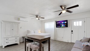 Ein modernes Schlafzimmer mit Bett, Nachttischen, einem Schreibtisch und einem Fernseher.