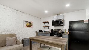 Eine moderne Küche mit weißen Wänden, einem Holztisch und einem schwarzen Kühlschrank.